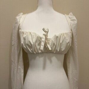 A white crop top with a low neck line, a central bonding detail for structure.